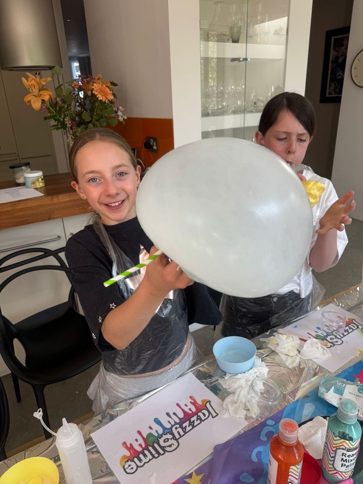 Two children holding up a giant slime bubble together