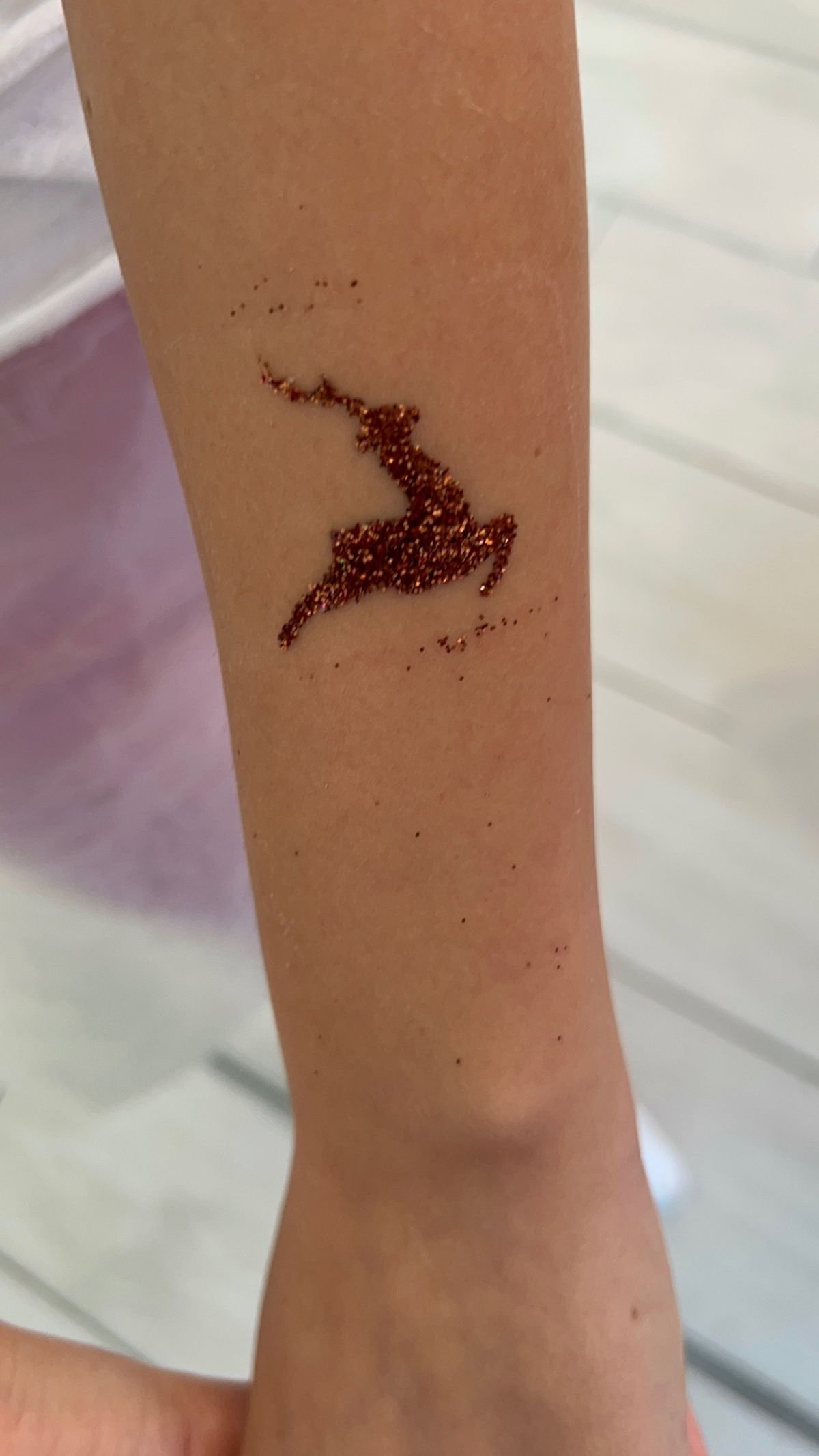A glitter tattoo in a deer design on a child's arm
