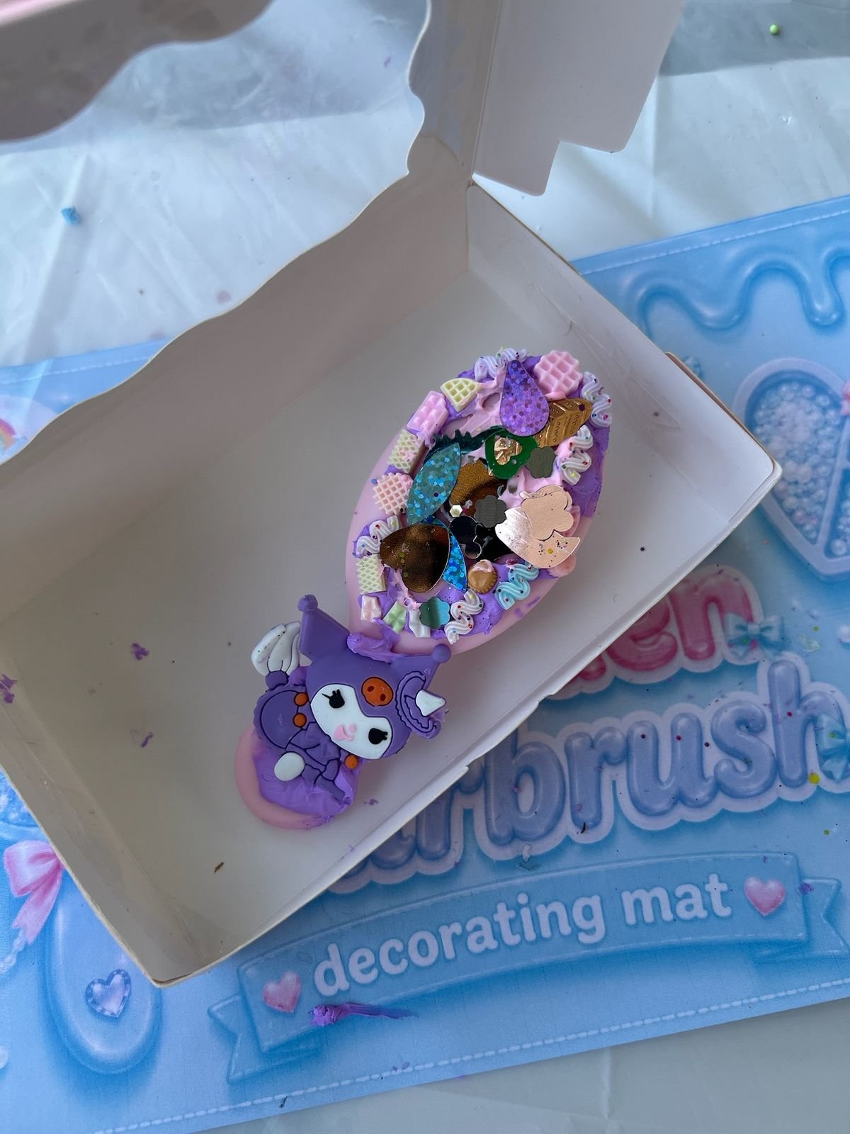 A mini hairbrush decorated in decoden style with a donut charm