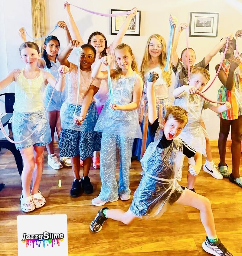 A group of children joyfully stretching slime ropes at a Jazzy Slime party